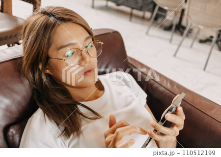 Bored woman using smartphone boringly in the cafe. Bored woman using smartphone boringly in the cafe. 110512199