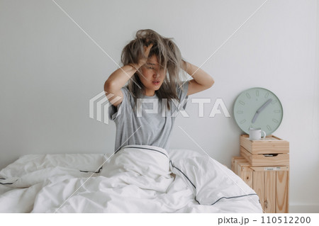 Woman just wake up by the at clock 7 AM on the bed in the morning. 110512200