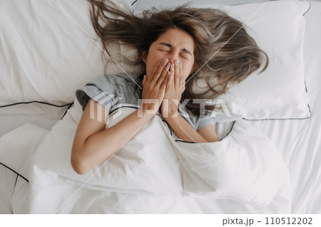 Top view of Yawning and stretching woman just wake up on the bed. Top view of Yawning and stretching woman just wake up on the bed. 110512202