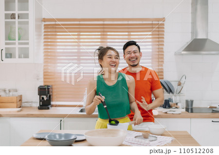 Funny husband fake to be happy with wife cooking. Funny couple in kitchen. Funny husband fake to be happy with wife cooking. Funny couple in kitchen. 110512208