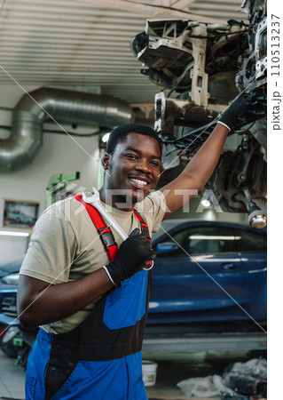 Portrait of young african man car service worker wearing uniform standing in garage 110513237