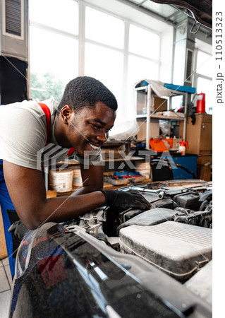 Young African male mechanic repairs car in garage close up Young African male mechanic repairs car in garage close up 110513323