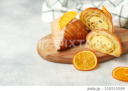 Glazed croissant with dried orange on wooden board Glazed croissant with dried orange on wooden board 110513584