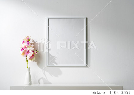 White wooden frame on white wall above the table 110513657