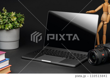 Open laptop with wooden mannequin on table against black background 110513841