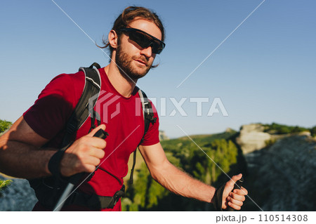 Young man hiker travels through the mountains with trekking poles for nordic walking 110514308