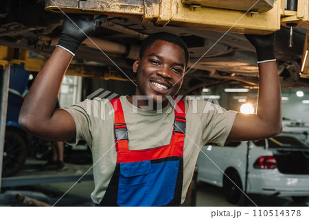 Portrait of young african man car service worker wearing uniform standing in garage 110514378