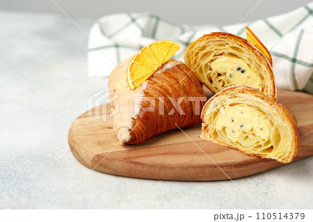 Glazed croissant with dried orange on wooden board 110514379