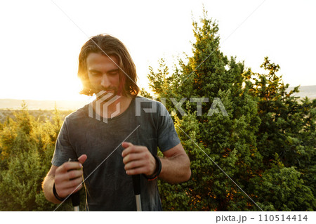 Young man hiker travels through the mountains with trekking poles for nordic walking 110514414