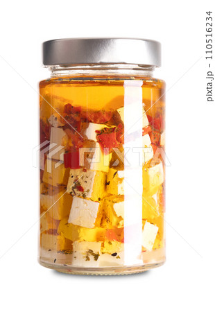 Feta cubes in oil, with red pepper and chili pieces, in glass jar. Greek cheese, matured in brine, with soft, moist texture, fresh, salty and acidic taste, cut in block shape, preserved in spiced oil. 110516234