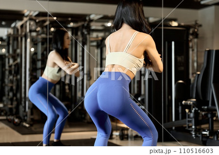 スクワットで下半身を鍛える女性 110516603