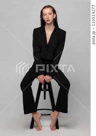 A beautiful slender girl in a black suit posing in the studio. A beautiful slender girl in a black suit posing in the studio. 110519277