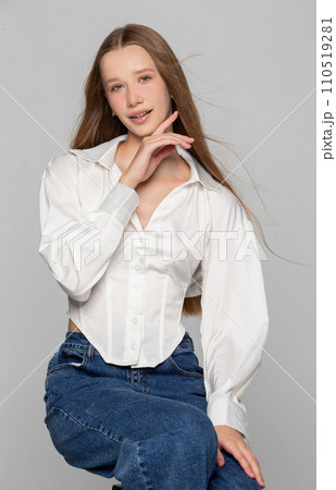 A girl in a white shirt and jeans on a gray background. Seventeen year old beauty. A girl in a white shirt and jeans on a gray background. Seventeen year old beauty. 110519281