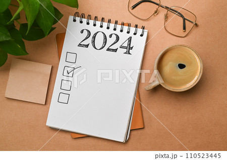 2024 goals list with notebook, coffee cup, plant and glasses on brown background. Plan, journal, to-do list 2024 goals list with notebook, coffee cup, plant and glasses on brown background. Plan, journal, to-do list 110523445