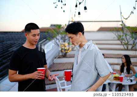 Happy young men chatting and drinking beer on a rooftop party. People lifestyle concept 110523493