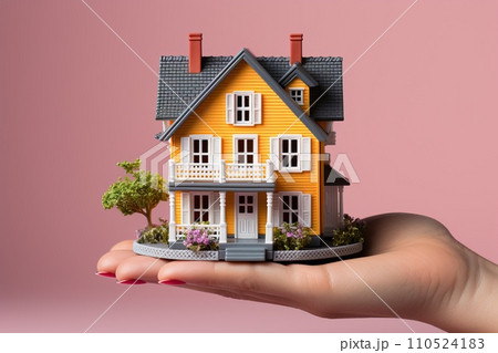 A man's hand holds a small house, a miniature of a family home. A man's hand holds a small house, a miniature of a family home. 110524183