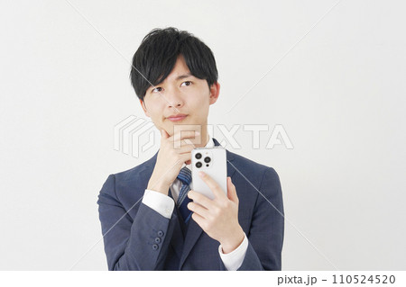 スマートフォンを見て考えるビジネスマン　白背景 110524520