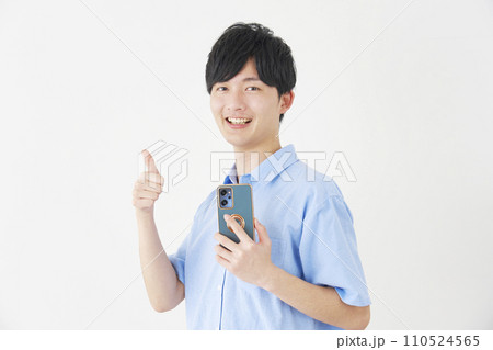スマートフォンを持ってグッドサインをする男性　白背景 110524565