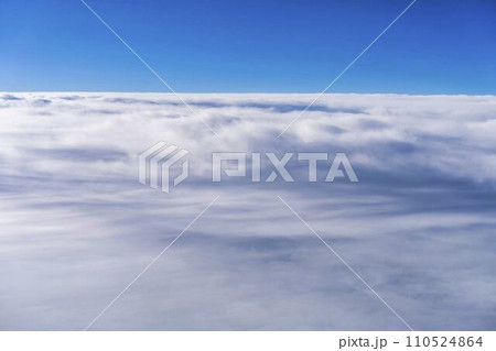 飛行機の窓から見た青空と雲海 110524864