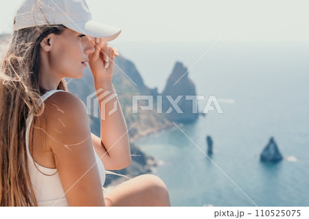 Woman summer travel sea. Happy tourist enjoy taking picture outdoors for memories. Woman traveler posing over sea bay surrounded by volcanic mountains, sharing travel adventure journey 110525075