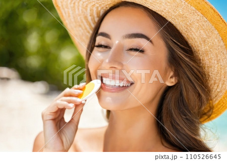 Smiling woman in hat is applying sunscreen on her face. AI 110526645