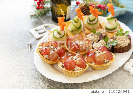 Creative appetizers set christmas. Christmas trees of ham, cucumber, cheese and star of carrot on crackers, tartlets with chicken and grapes, creamy pate sandwiches of herring on a rye bread. Copy Creative appetizers set christmas. Christmas trees of ham, cucumber, cheese and star of carrot on crackers, tartlets with chicken and grapes, creamy pate sandwiches of herring on a rye bread. Copy 110526941