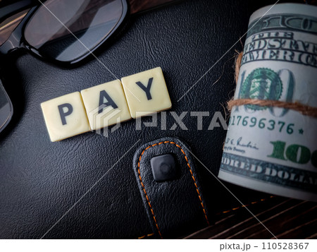 Top view banknotes,glasses and toys word with text PAY on wooden background. 110528367