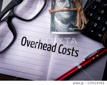 Top view pen,calculator,banknotes,glasses with text Overhead Costs. 110528368