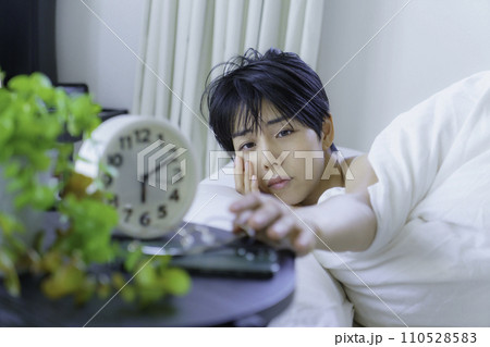 朝ベッドから起きて目覚まし時計を止めようとする若い女性 朝ベッドから起きて目覚まし時計を止めようとする若い女性 110528583