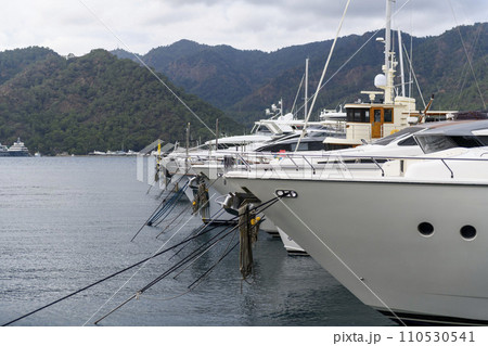 Row of super yachts moored in marina fore side view. Mediterranean yacht port with sailing boats. Yachting concept. Row of super yachts moored in marina fore side view. Mediterranean yacht port with sailing boats. Yachting concept. 110530541