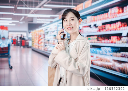 スマホを使いながらスーパーで買い物をする主婦 スマホを使いながらスーパーで買い物をする主婦 110532392