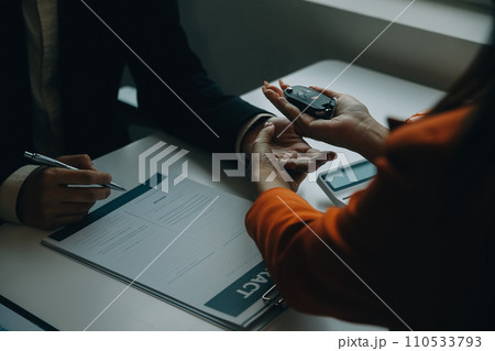 Closeup asian male people car salesman or sales manager offers to sell a car and explains and reads the terms of signing a car contract and insurance. 110533793