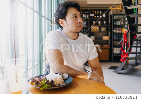 Asian man in white t-shirt waiting for someone to meet at the restaurant. 110533911