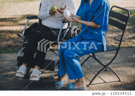 nurse with elderly man in wheelchair at park 110534511