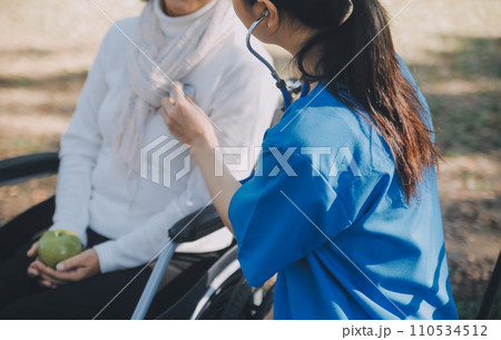 nurse with elderly man in wheelchair at park nurse with elderly man in wheelchair at park 110534512