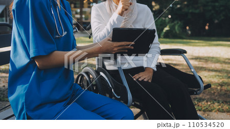 nurse with elderly man in wheelchair at park nurse with elderly man in wheelchair at park 110534520