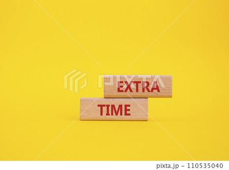 Extra time symbol. Concept word Extra time on wooden blocks. Beautiful yellow background. Business and Extra time concept. Copy space Extra time symbol. Concept word Extra time on wooden blocks. Beautiful yellow background. Business and Extra time concept. Copy space 110535040