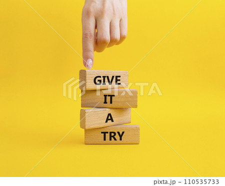 Give it a try symbol. Concept words Give it a try on wooden blocks. Beautiful yellow background. Businessman hand. Business and Give it a try concept. Copy space. 110535733
