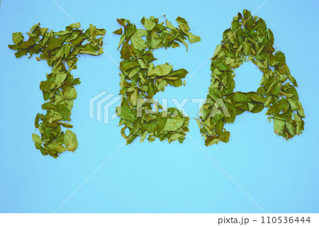 Inscription with letters Tea, dried herbal leaves of fruit trees on turquoise 110536444