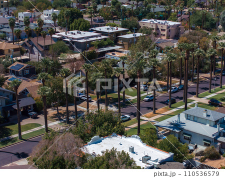 An aerial shot of Californian palms with an empty road. Palm trees and desert mountain in Palm Springs, California. An aerial shot of Californian palms with an empty road. Palm trees and desert mountain in Palm Springs, California. 110536579