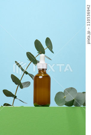 A glass brown bottle with a dropper on a blue background, a container for cosmetic products. A glass brown bottle with a dropper on a blue background, a container for cosmetic products. 110536942