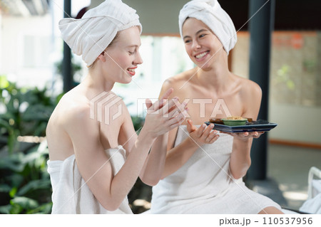 Two attractive woman in towel giggling during hold the herbal bowl. Tranquility. Two attractive woman in towel giggling during hold the herbal bowl. Tranquility. 110537956