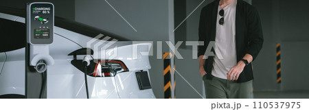 Young man travel with EV electric car to shopping center parking lot innards 110537975