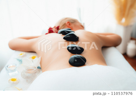 Hot stone massage at spa salon in luxury resort. Quiescent Hot stone massage at spa salon in luxury resort. Quiescent 110537976