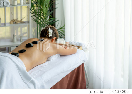 Hot stone massage at spa salon in luxury resort. Quiescent Hot stone massage at spa salon in luxury resort. Quiescent 110538009