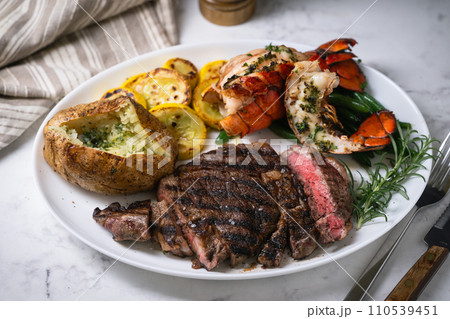 surf and turf, ribeye steak and lobster tail on white marble background 110539451