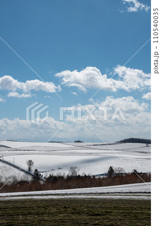 雪が溶け始めた畑と丘陵地帯 雪が溶け始めた畑と丘陵地帯 110540035