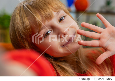 Child kid girl taking selfie on smartphone communicating video call home online with subscribers Child kid girl taking selfie on smartphone communicating video call home online with subscribers 110541305