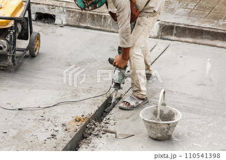 Construction worker using jackhammer drilling concrete surface 110541398