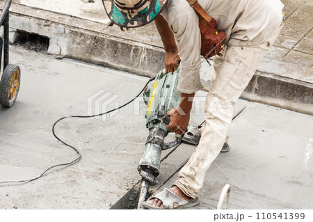 Construction worker using jackhammer drilling concrete surface 110541399